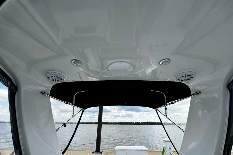Slide: The Image of 2022 Monterey 295 Sport Yacht interior view with speakers and canopy, overlooking a serene water scene. - 38