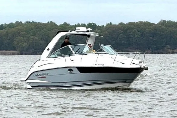 Slide: The Image of 2022 Monterey 295SS Super Sport boat cruising on a lake with forested shoreline. - 10