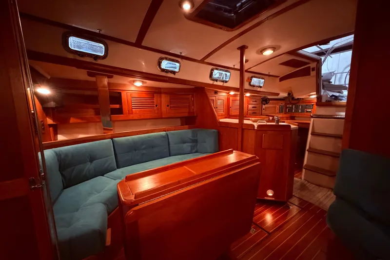 Slide: The Image of Interior of a 2000 Tartan 3500 sailboat with wooden furnishings and blue seating. - 12