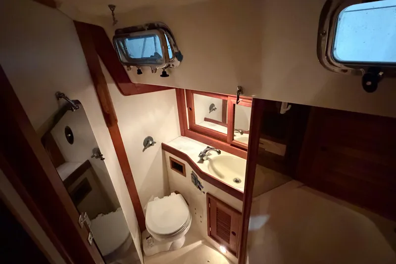 Slide: The Image of Bathroom interior of a 2000 Tartan 3500 yacht, featuring sink, toilet, and porthole window. - 14