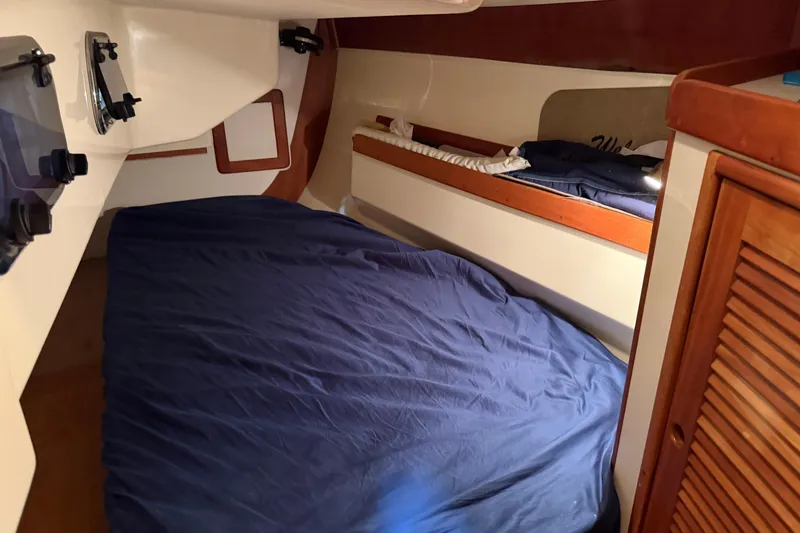 Slide: The Image of Cozy cabin interior of a 2000 Tartan 3500 sailboat with blue bedding and wooden accents. - 20