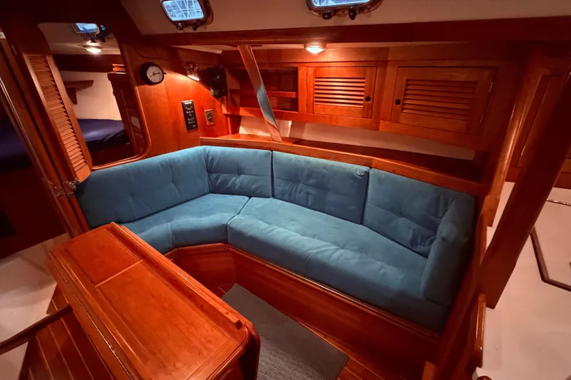 Slide: The Image of Interior of a 2000 Tartan 3500 yacht with blue cushioned seating and wooden cabinetry. - 8