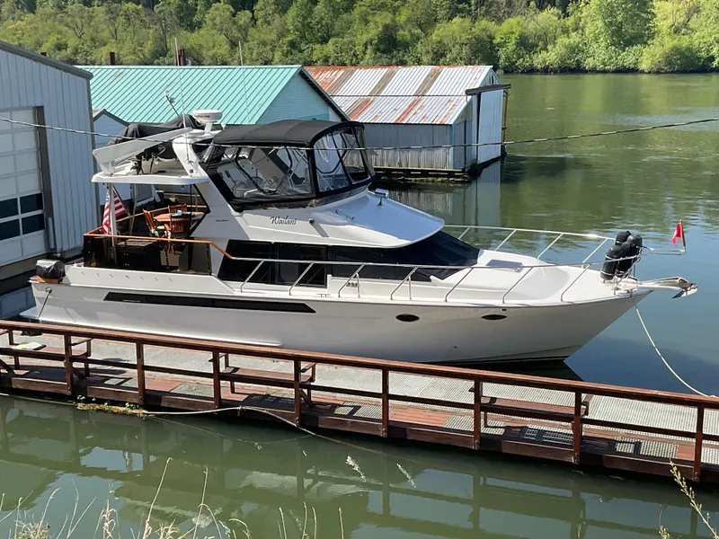 Slide: The Image of 1990 Ocean Alexander 440 Sundeck CPMY docked by a serene river. - 2