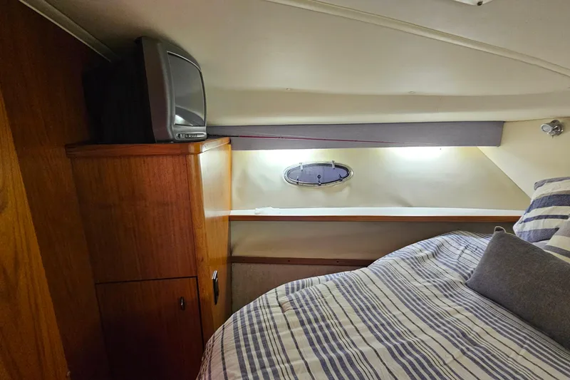 Slide: The Image of Cozy cabin interior of 2000 Tiara Yachts 3500 Open with striped bedding and vintage TV. - 23