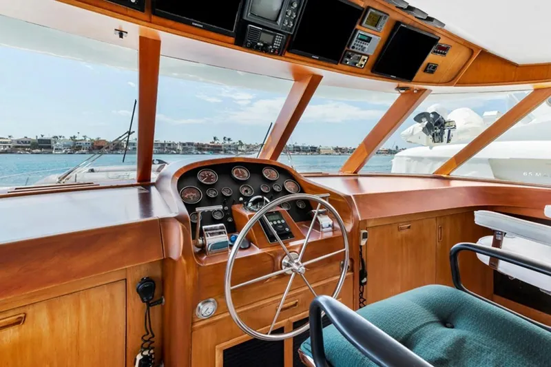 Slide: The Image of Helm of 1983 Elliott Yacht Fisher with wooden dashboard and steering wheel, overlooking marina. - 3