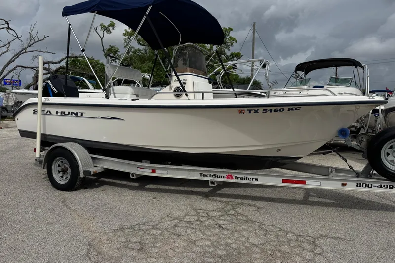 The Image of 2004 Sea Hunt Triton 186 boat on trailer, parked outdoors under cloudy sky. - 1