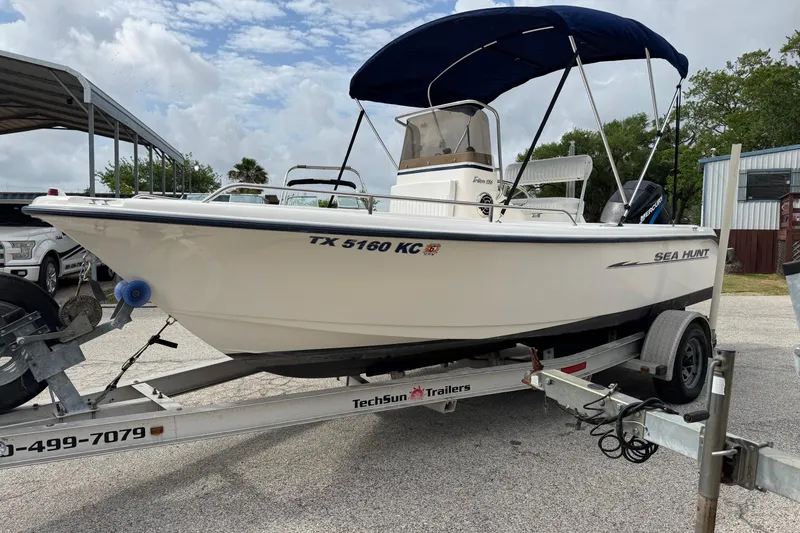 Slide: The Image of 2004 Sea Hunt Triton 186 boat on trailer with blue canopy, parked outdoors. - 3