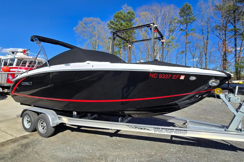 The Image of 2016 Cobalt R3 boat on trailer, black with red stripe, parked outdoors. - 0