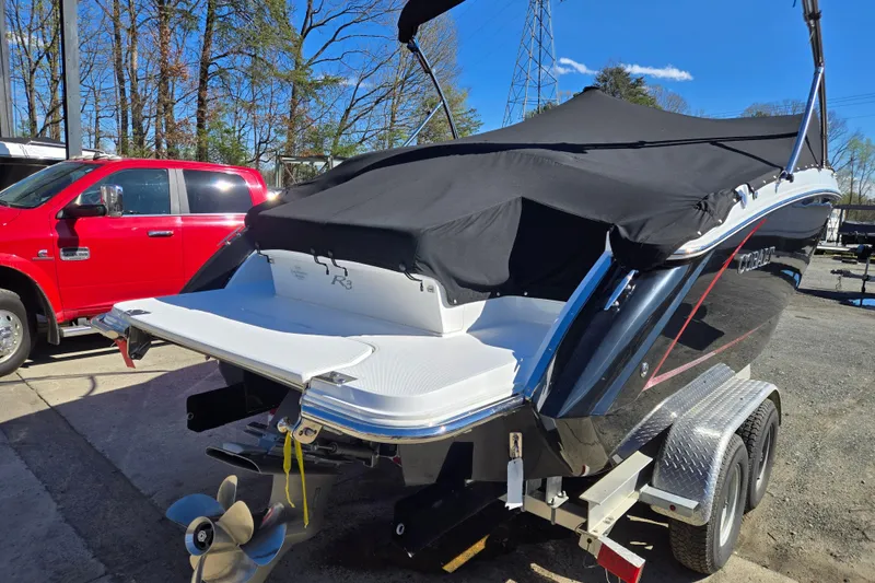Slide: The Image of 2016 Cobalt R3 boat on trailer, covered, with red vehicle nearby. - 2