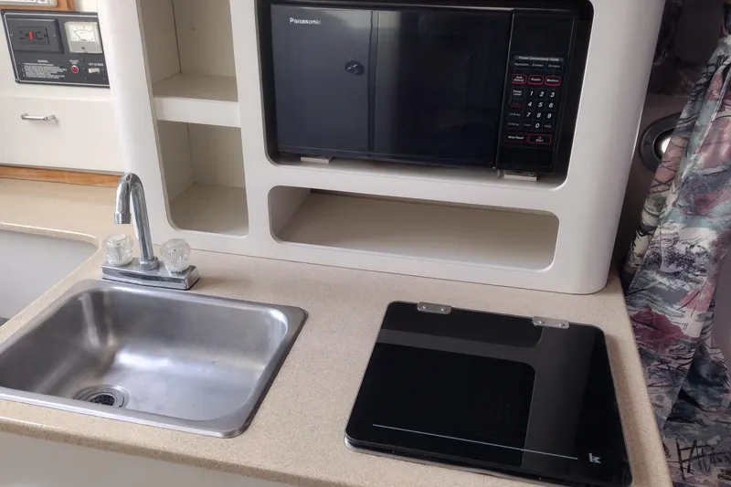 Slide: The Image of 1996 Crownline 250 CR boat kitchen with sink, microwave, and countertop. - 13