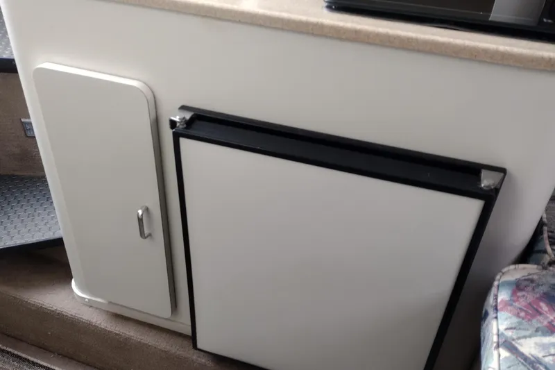 Slide: The Image of 1996 Crownline 250 CR boat interior with compact fridge and storage cabinet. - 14