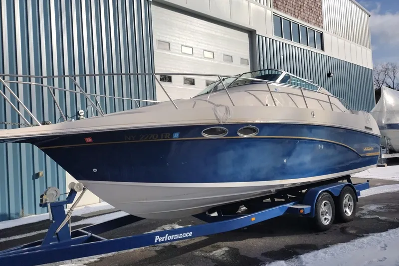 Slide: The Image of 1996 Crownline 250 CR boat on trailer, parked outside a warehouse. - 3