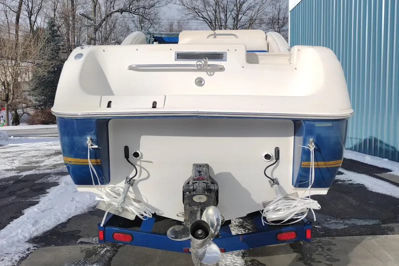 Slide: The Image of 1996 Crownline 250 CR boat rear view, parked on snowy ground near a blue building. - 7