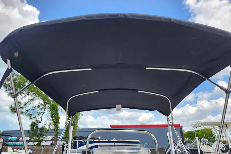 Slide: The Image of 2022 Carolina Skiff 178 JLS boat with black canopy under blue sky. - 21