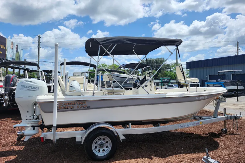 Slide: The Image of 2022 Carolina Skiff 178 JLS boat on trailer with Suzuki outboard motor, under blue sky. - 8