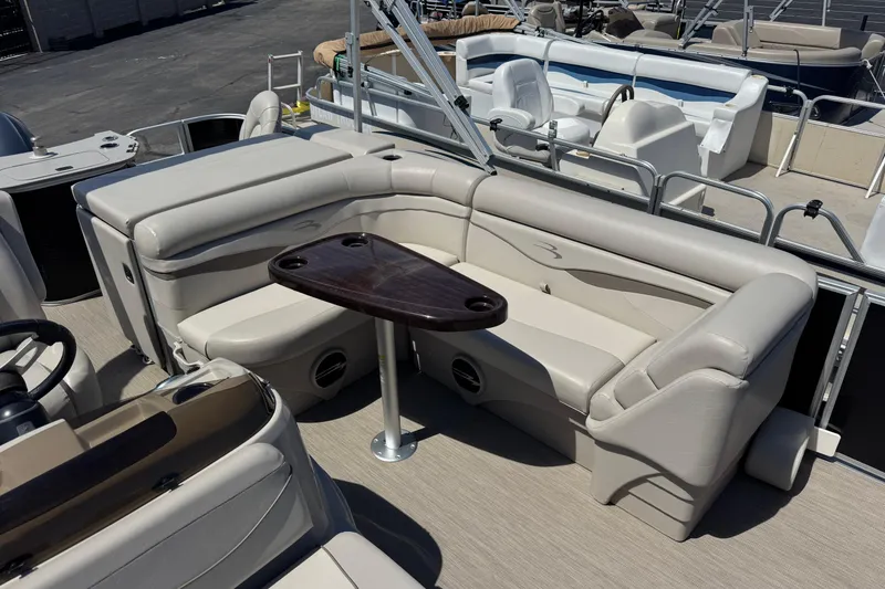 Slide: The Image of 2017 Bennington 22 SX Fish pontoon boat interior with beige seating and dark wood table. - 10