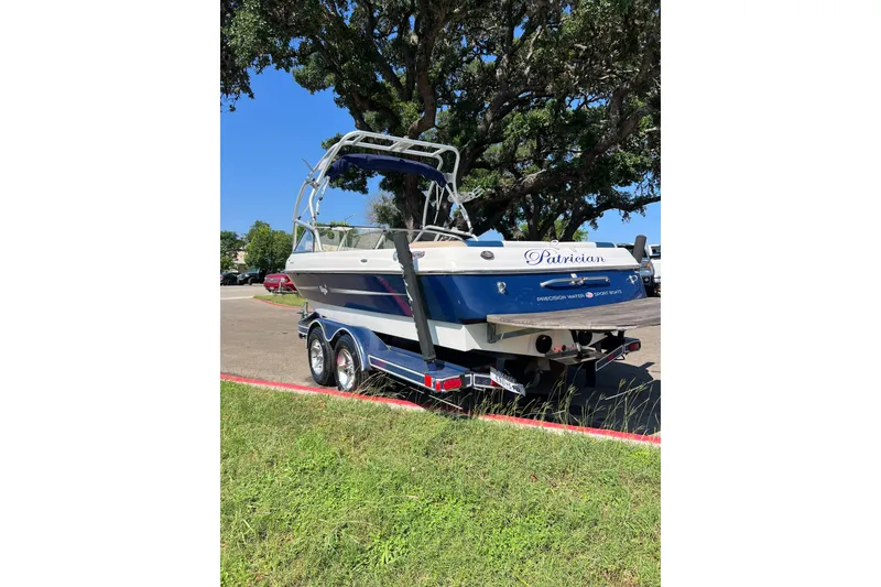 Slide: The Image of 2004 Tigé 21i Limited Edition boat on trailer, parked near trees. - 6