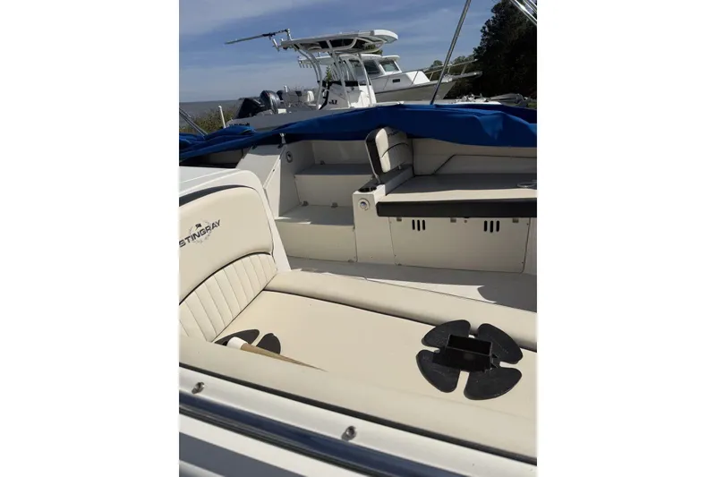 Slide: The Image of 2021 Stingray 212 SC boat interior with seating and cup holder, docked outdoors. - 10