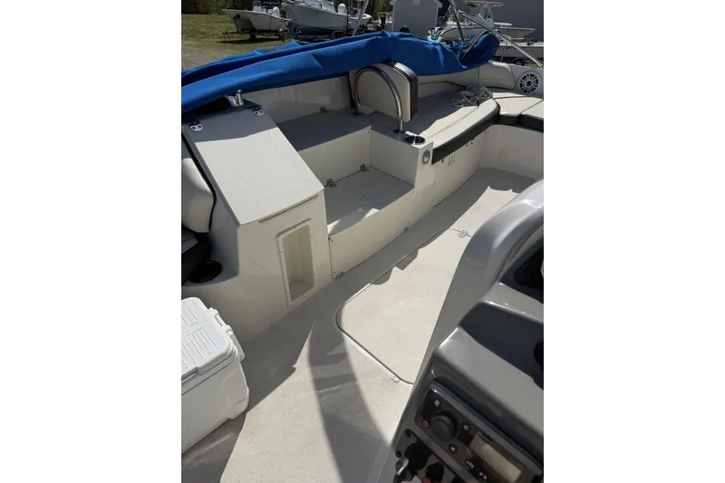 Slide: The Image of 2021 Stingray 212 SC boat interior with seating and storage, featuring a blue cover. - 12