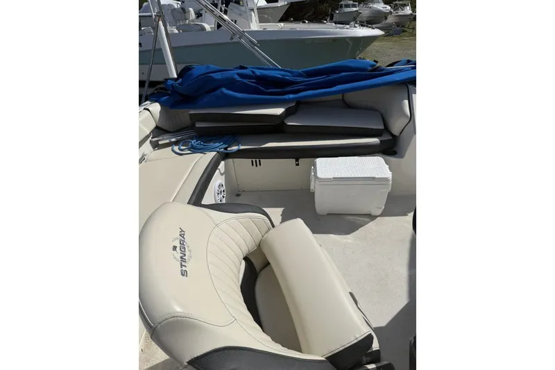 Slide: The Image of 2021 Stingray 212 SC boat interior with seating, cooler, and blue cover. - 13