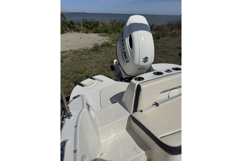 Slide: The Image of 2021 Stingray 212 SC boat with Suzuki outboard motor, parked near a scenic waterfront. - 14