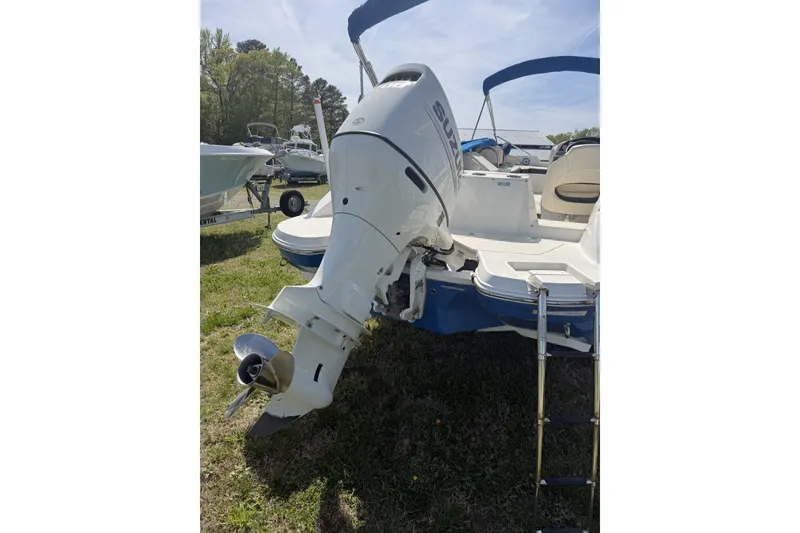 Slide: The Image of 2021 Stingray 212 SC boat with Suzuki outboard motor and swim ladder, parked on grass. - 15