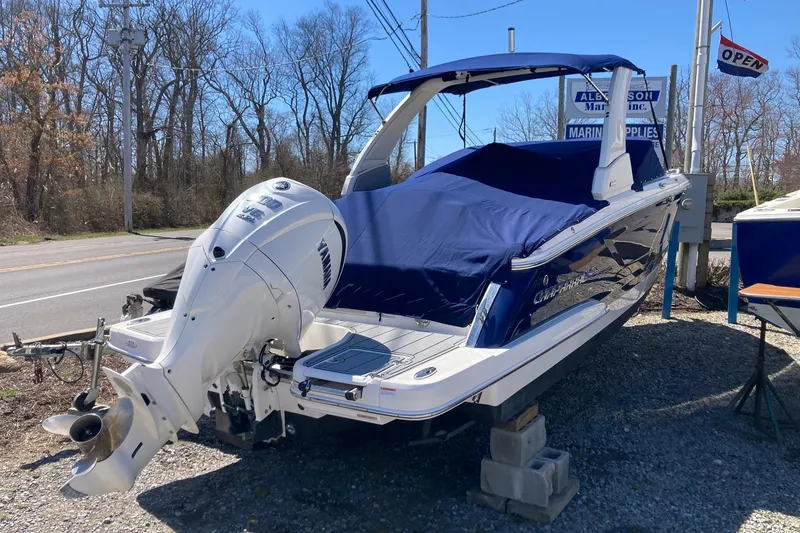 Slide: The Image of 2022 Chaparral 267 SSX OB boat with blue cover and outboard motor displayed outdoors. - 3