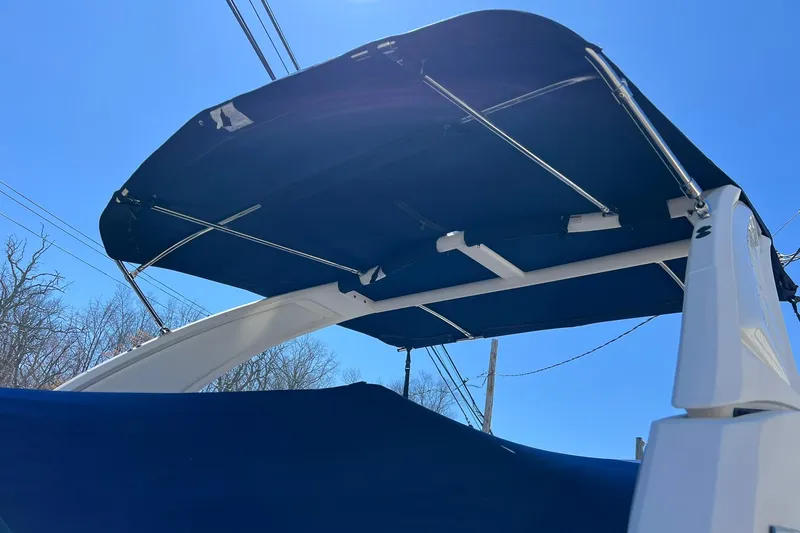 Slide: The Image of 2022 Chaparral 267 SSX OB boat with blue canopy under clear sky. - 5