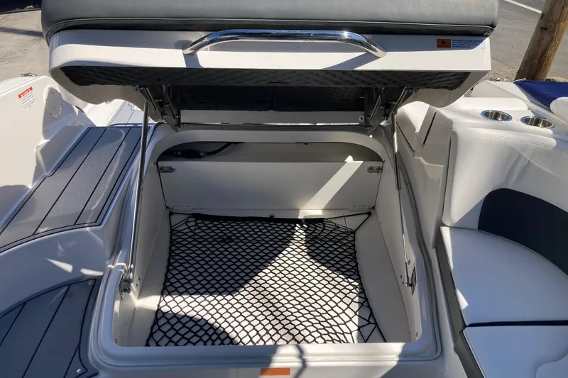 Slide: The Image of 2022 Chaparral 267 SSX OB boat storage compartment with open lid and netting. - 8
