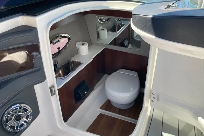Slide: The Image of 2022 Chaparral 267 SSX OB boat interior with toilet, sink, and wood accents. - 9