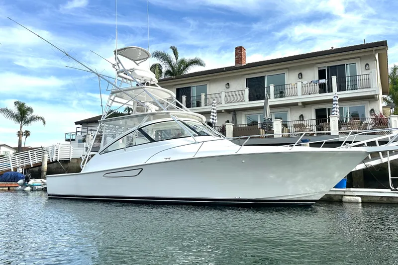 The Image of 2012 Viking 42 Open yacht docked by a waterfront home, under a clear blue sky. - 0