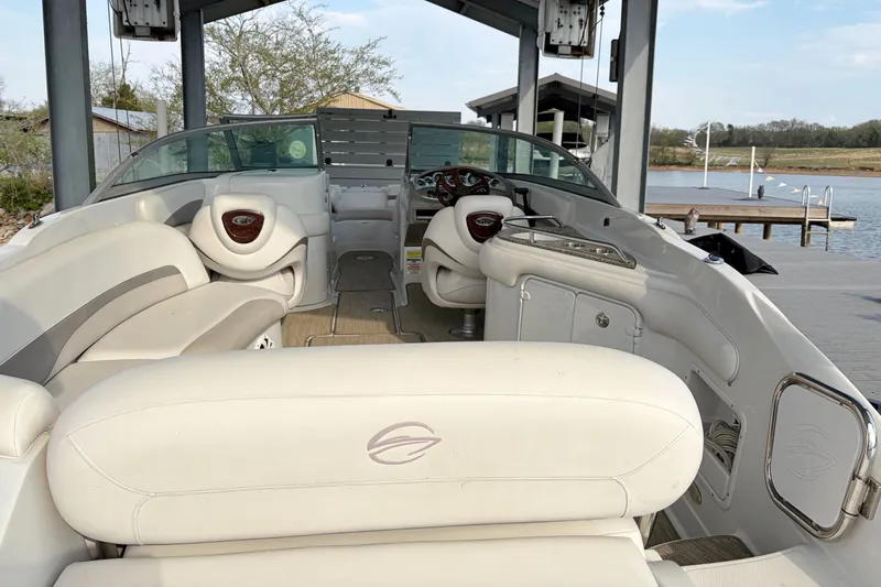Slide: The Image of 2007 Crownline 252 EX boat interior with white seating, docked by a serene lake. - 7
