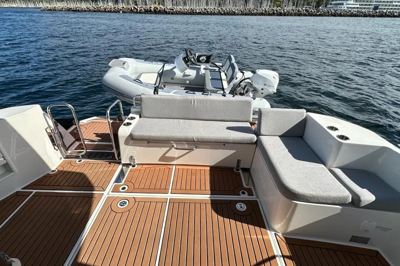 Slide: The Image of 2024 Beneteau Swift Trawler 41 Sedan deck with seating and tender on water. - 22