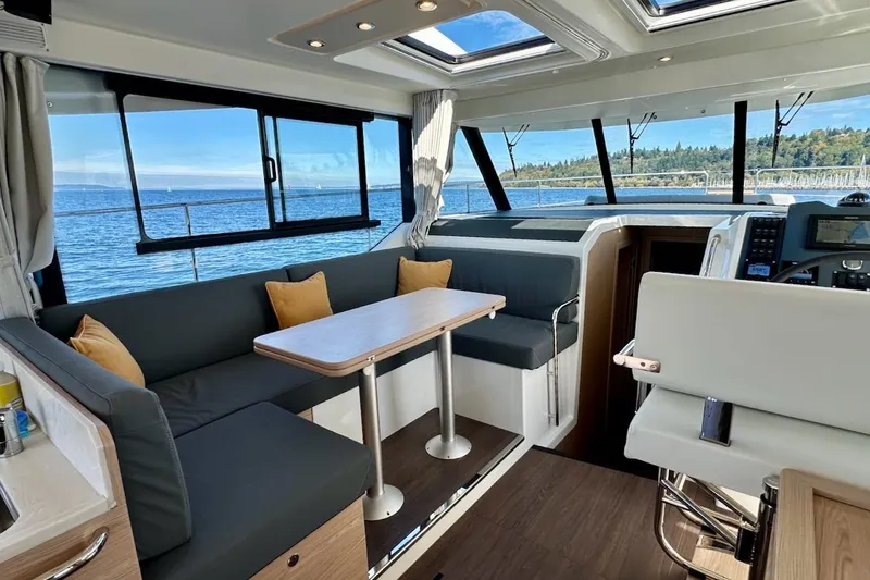 Slide: The Image of 2024 Beneteau Swift Trawler 41 Sedan interior with ocean view, featuring modern seating and navigation area. - 50