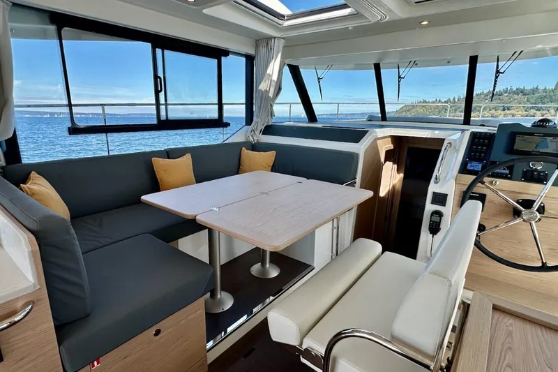 Slide: The Image of Interior of 2024 Beneteau Swift Trawler 41 Sedan with seating and helm, overlooking ocean. - 51