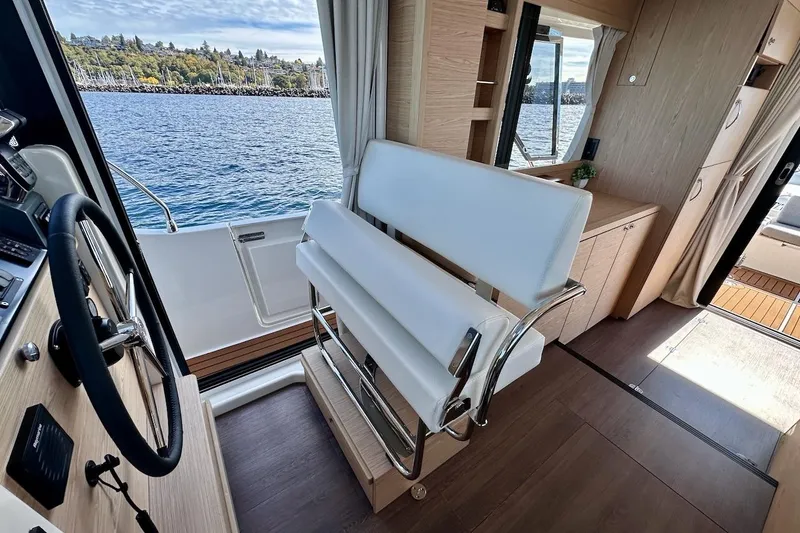 Slide: The Image of Interior of 2024 Beneteau Swift Trawler 41 Sedan with helm and seating, overlooking water. - 56