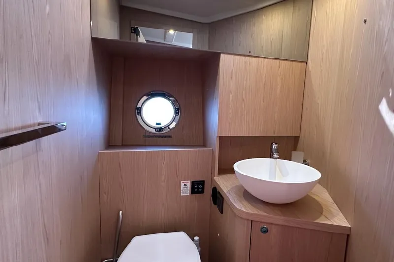 Slide: The Image of 2024 Beneteau Swift Trawler 41 Sedan bathroom with modern sink and porthole window. - 69