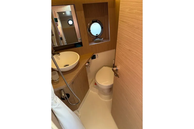 Slide: The Image of 2024 Beneteau Swift Trawler 41 Sedan bathroom with sink, toilet, and porthole window. - 71
