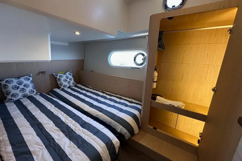 Slide: The Image of 2024 Beneteau Swift Trawler 41 Sedan cabin with twin beds and wooden storage. - 74