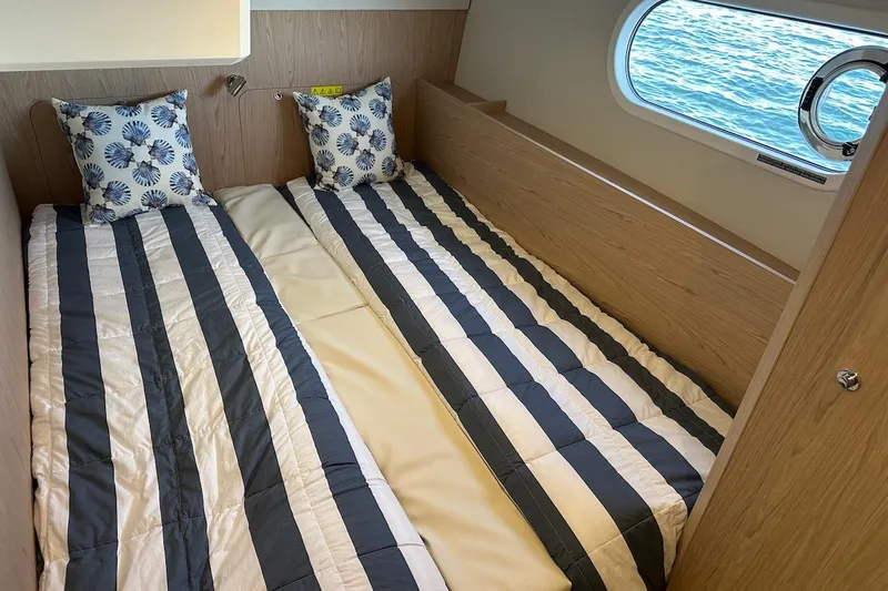 Slide: The Image of Twin beds in the 2024 Beneteau Swift Trawler 41 Sedan cabin with nautical decor. - 75