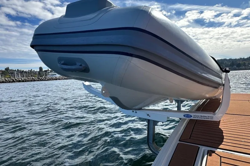 Slide: The Image of 2024 Beneteau Swift Trawler 41 Sedan with mounted dinghy on deck, scenic water view. - 91