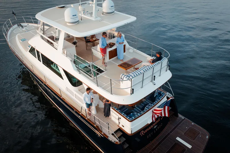 Slide: The Image of 2027 Hunt Yachts 63 Flybridge on water, people enjoying the deck, American flag displayed. - 17