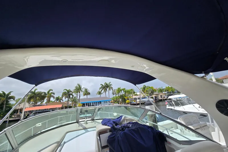 Slide: The Image of 2006 Sea Ray Sundancer 320 boat with canopy, docked near palm trees and waterfront homes. - 11