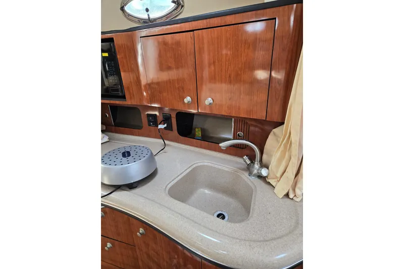Slide: The Image of 2006 Sea Ray Sundancer 320 galley with wooden cabinets and sink. - 21