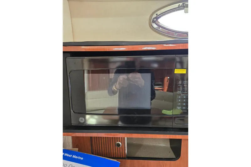 Slide: The Image of Microwave inside 2006 Sea Ray Sundancer 320 yacht, featuring wood cabinetry and oval window. - 24