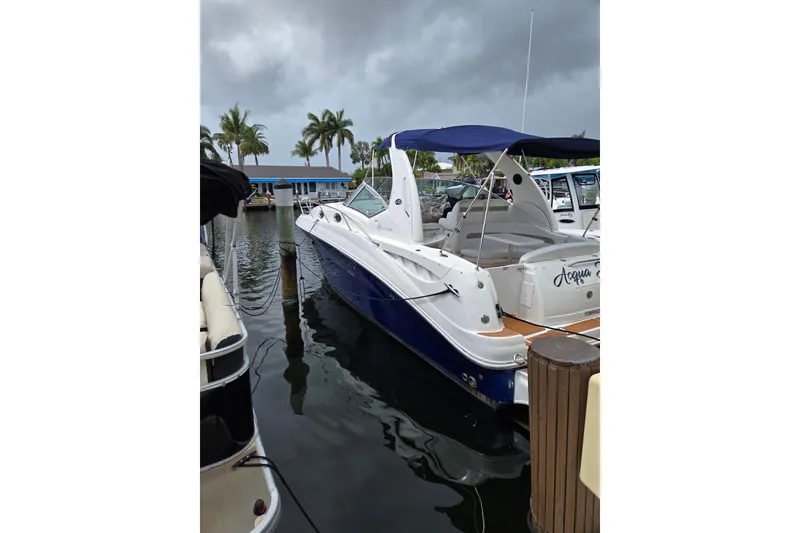 Slide: The Image of 2006 Sea Ray Sundancer 320 docked at marina, under cloudy sky with palm trees. - 32