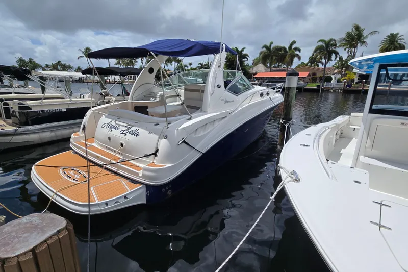 Slide: The Image of 2006 Sea Ray Sundancer 320 docked at marina, featuring sleek design and blue canopy. - 4