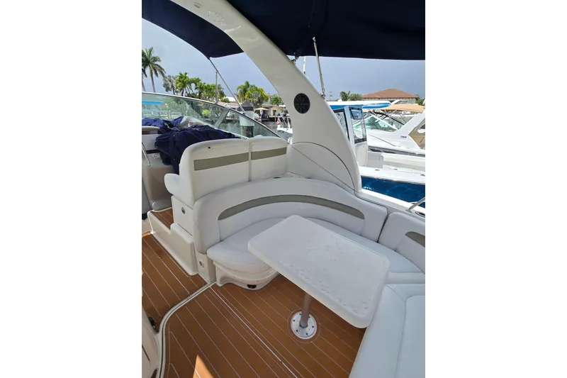 Slide: The Image of 2006 Sea Ray Sundancer 320 interior with seating and table, docked near other boats. - 6