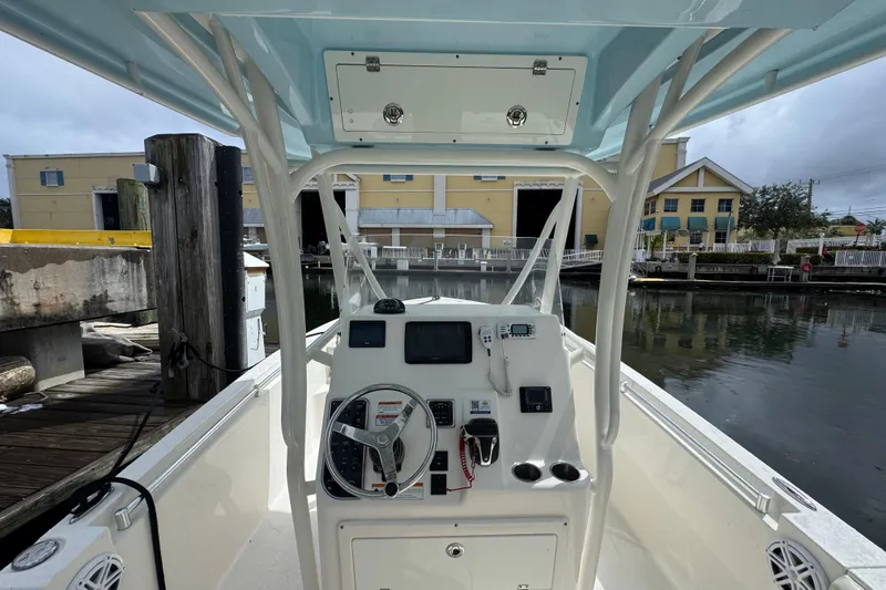 Slide: The Image of 2021 Cobia 237 Center Console boat at dock, featuring helm and controls. - 10
