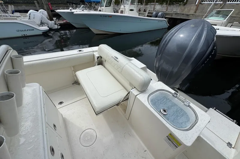 Slide: The Image of 2021 Cobia 237 Center Console boat interior with seating and motor, docked near other boats. - 11